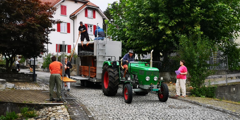 Freiwillige Helfer laden die Stände von einem Traktor ab und bauen die Marktstände auf