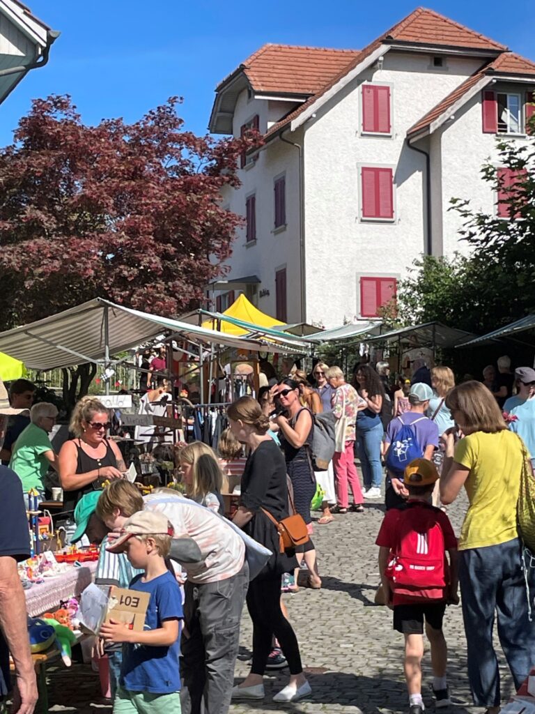 Marktbesucher:innen flanieren entlang den Marktständen