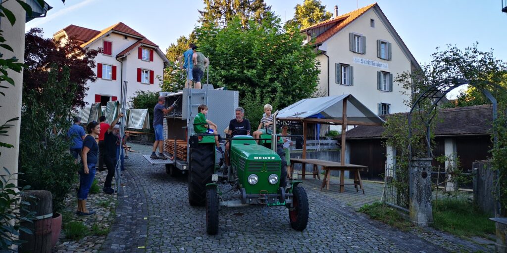 Traktor mit aufgeladenen Marktständen. Leute bauen die Stände auf.